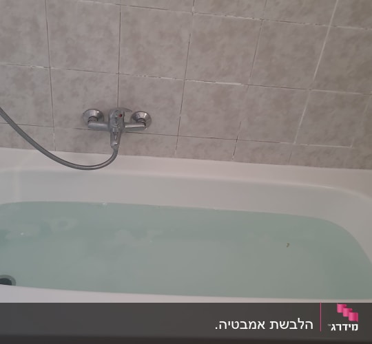אמבטיה עם מים וקיר אריחים